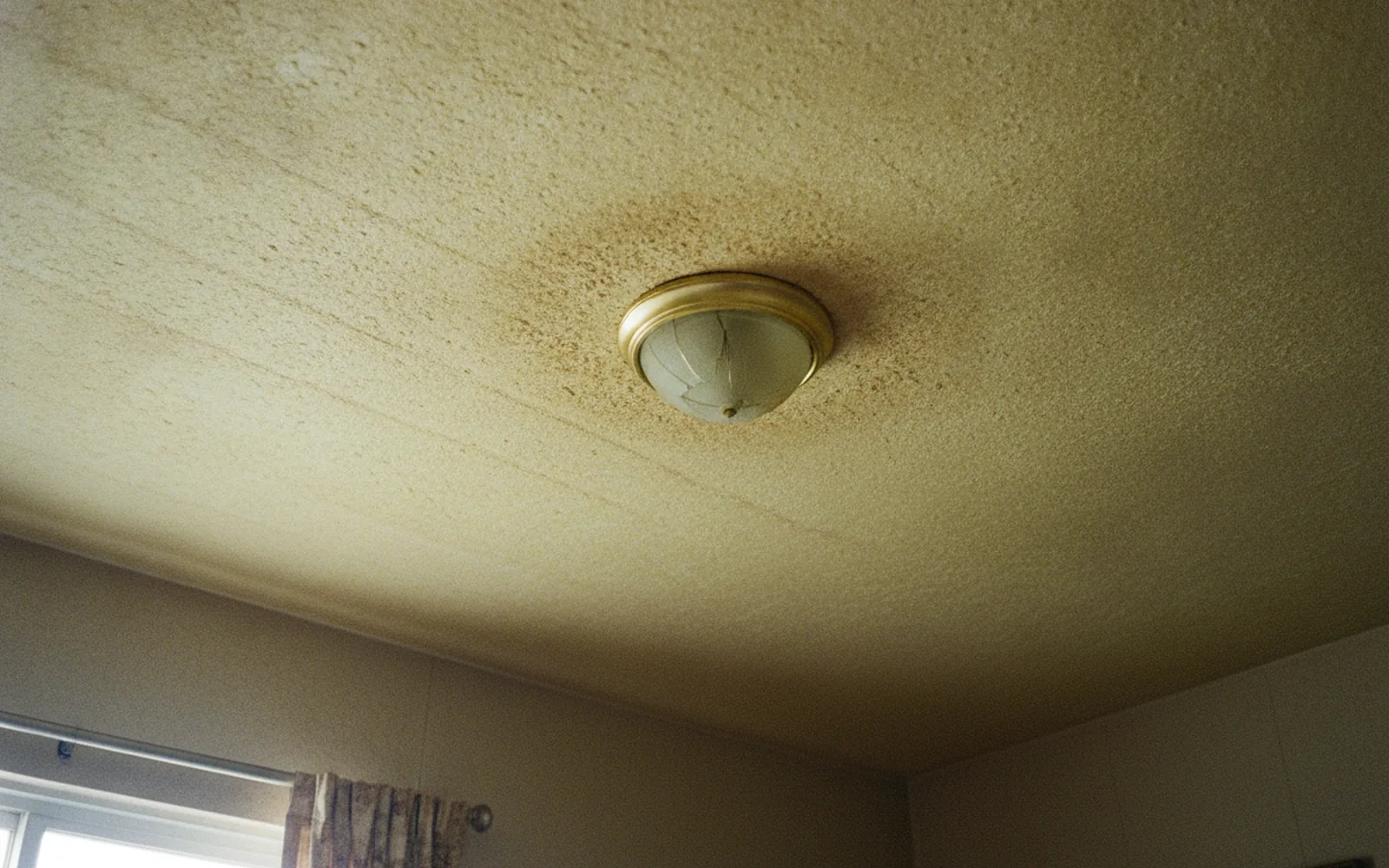 Textured popcorn ceiling with a water stain in an Austin house before removal